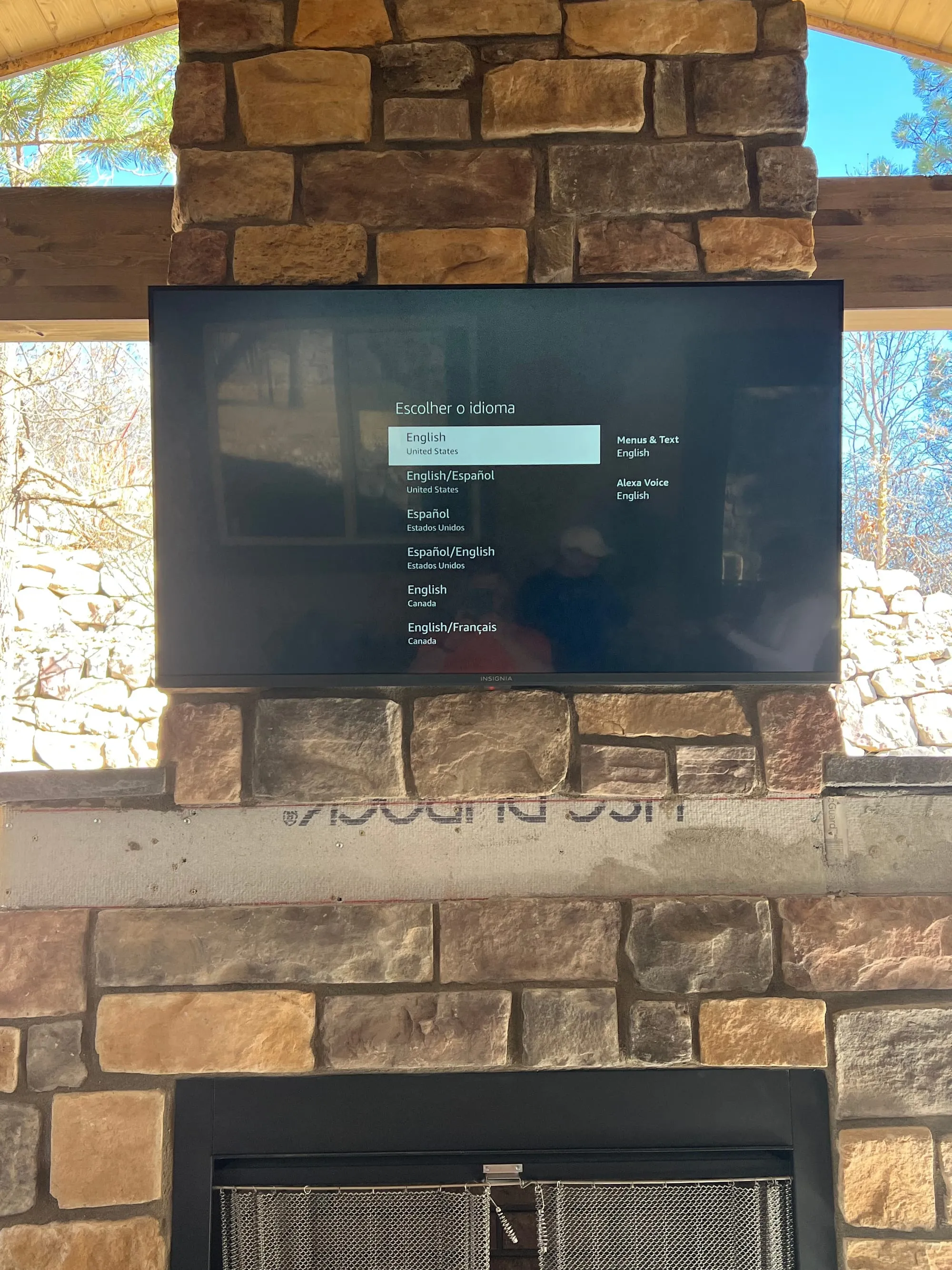 Outdoor TV mounted on a stone wall under a covered patio